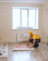 Builders doing apartment repair. Construction workers wallpapering new apartment. Home renovation works.